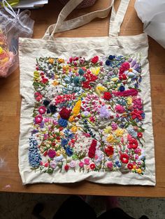 an embroidered bag sitting on top of a wooden table