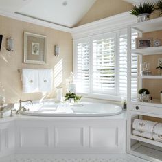 a large white bath tub sitting in a bathroom next to a window with shutters