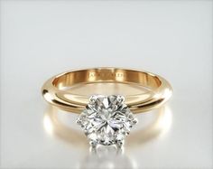 an engagement ring with a round diamond in the center and a gold band around it