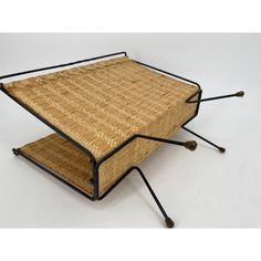 an unusual coffee table made out of wicker and black metal legs, with one section folded down to the side