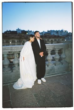 a man and woman standing next to each other in front of a cityscape