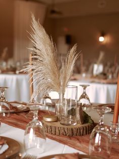 the table is set with wine glasses, silverware and pamodia in glass vases