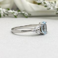 a close up of a ring on a white surface with flowers in the back ground