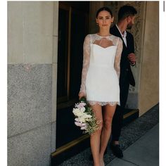 a woman in a short white dress is walking down the street with a man behind her