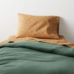 an unmade bed with green linens and polka dot pillow cases on the headboard