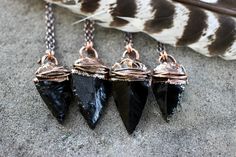 "This listing is for one black obsidian arrowhead pendant necklace. These beautiful and richly black obsidian arrowheads are wrapped in copper wire and set in copper \"skin.\" They are elegant, yet edgy and irresistibly raw and organic. The wire setting is encased in a thick copper setting and is unique and interesting. The back has the wire looped in a neat and rustic knot. I create these necklaces with a technique called electroforming. Copper is deposited over the stone over 12-24 hours using Handmade Black Arrowhead Jewelry, Handmade Black Arrowhead Necklace, Wrapped Gemstones, Arrowhead Pendant Necklace, Black Stone Necklace, Witchy Necklace, Gemstones Pendant, Obsidian Arrowhead, Arrowhead Pendant