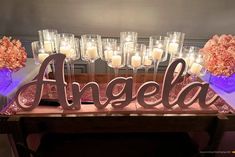 a table with candles and flowers on it that says angella in front of them