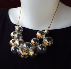 Unique and chic, This Glass beads bib necklace, for sure is a conversation starter. This Clear and Gold bubbles statement necklace combines transparent hollow glass beads, Filled with pieces of 22 karat gold leaf, in a cluster shape, connected to a Leather cord, and closes with a goldfilled clasp. The necklace has 2 inches (5 cm) chain to adjustable length. You can pair this unique necklace with these earrings: https://etsy.me/3Qg86lX This bold-blown airy jewelry is light and easy to wear, Perfe Gold Bubbles, Beaded Bib Necklace, Bubble Necklaces, Handmade Glass Beads, Unique Necklace, Chic Jewelry, Leaf Necklace, Beaded Necklaces, Bib Necklace