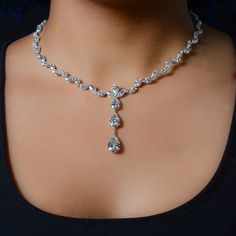 a woman wearing a diamond necklace and choker on her neck with an earring in the shape of a tear