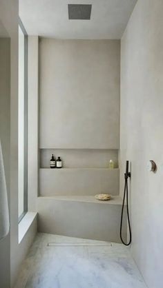 a bathroom with a tub, shower head and shelves on the wall next to it