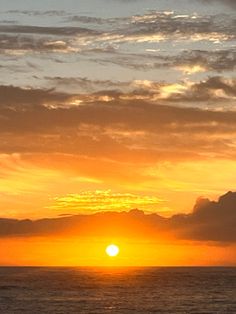 the sun is setting over the ocean with clouds in the sky and water below it