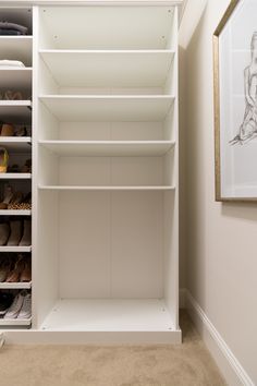 a closet with white shelves and shoes on the bottom shelf in front of a painting