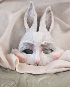 a white rabbit mask laying on top of a bed