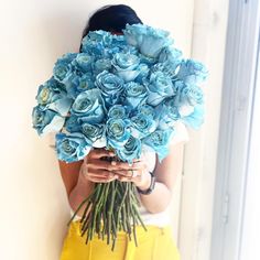 a woman holding a bouquet of blue roses