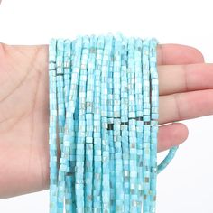 a hand is holding several strands of blue glass beads