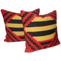 two red, black and yellow pillows on a white background with the same color pattern