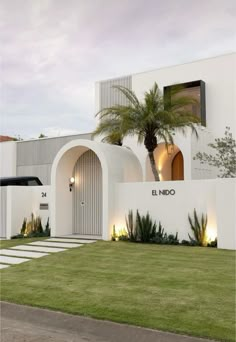 a white building with palm trees and lights on it's front door is lit up at night