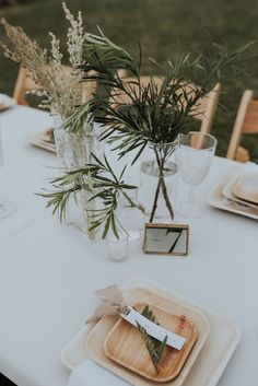 the table is set with place settings and flowers in vases on top of plates