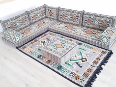 a corner couch with an intricately designed rug on the floor