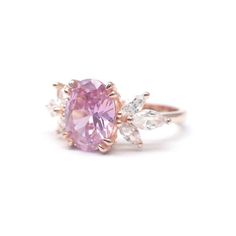 a pink ring with three white diamonds on top and an oval shaped stone in the middle