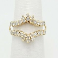 two wedding rings on top of each other with white stones in the middle and yellow gold