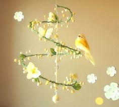 a yellow bird sitting on top of a branch with white flowers hanging from it's side