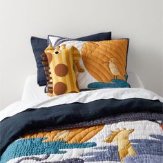 a bed topped with two pillows and a stuffed giraffe