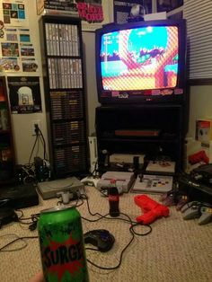 a person holding a can in front of a tv with video games on the screen