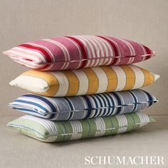 four pillows stacked on top of each other in different colors and patterns, with the words schumachier above them