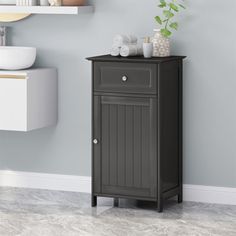 a bathroom with gray walls and white shelves on the wall, along with a black cabinet