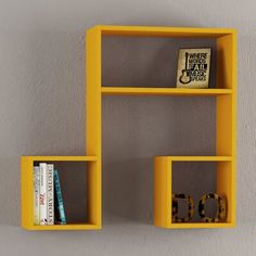 two yellow shelves with books on them against a gray wall, one is shaped like the letter d