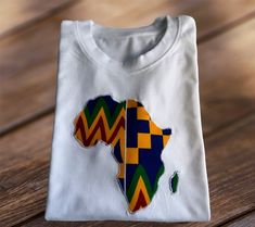 This T-shirt with a vibrant print motif is unisex and perfect for casual outings.  The vibrant appliquéd African Map in Kente fabric is satin stitched all around to ensure durability. Materials:  T-Shirt - 100% Cotton Appliqué - 100% African Wax Print Size Fits an 11 Year Old Zambian Flag, Kente Fabric, African Map, African Wax Print, Boys Clothes, Satin Stitch, Wax Print, African Inspired, African Print