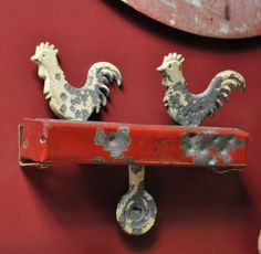 two rooster figurines sitting on top of a red shelf