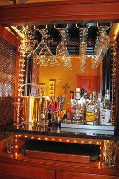 a bar with lights and liquor bottles on the counter in front of a mirror that is lit up