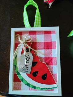 a watermelon shaped ornament hanging from a ribbon