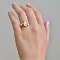 a woman's hand with a yellow gold ring on it and a diamond in the middle