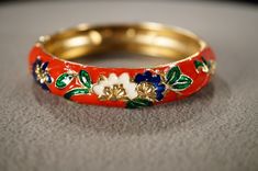 I  am offering you this antique vintage yellow gold tone eternity design bangle bracelet. This features a domed etched scrolled raised relief  multi colored enameled design to it ! It measures app. 2.5 inch inches in diameter. It measures app. 1/2 inch wide. This came out of an estate here in upstate New York where I uncovered several very older but fashion forward pieces of collectible jewelry , this gorgeous bracelet is no exception. Please review all of my pictures, as they are all a very imp Vintage Enamel Bangle Jewelry, Vintage Enamel Bangle As A Gift, Vintage Enamel Bangle As Gift, Vintage Enamel Bangle For Gift, Traditional Gold Enamel Bangle, Vintage Enamel Bangle Gift, Hand Painted Gold Bracelet, Vintage Round Enamel Bangle, Vintage Multicolor Enamel Bangle