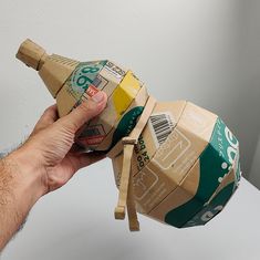 a hand holding an open can of soda wrapped in brown paper