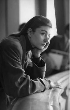 black and white photograph of a woman leaning on a wall with her hand under her chin