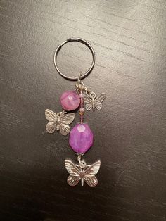 a keychain with two butterflies and a pink bead hanging from it's side