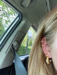 a woman wearing ear rings in the back seat of a car