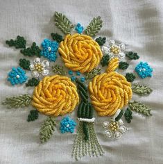 a bouquet of yellow flowers is on a white cloth with blue and green trimmings