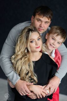 a man and woman are posing for a photo with their young son, who is wearing a ring