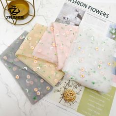 four pieces of cloth with flowers on them sitting on top of a table next to a magazine