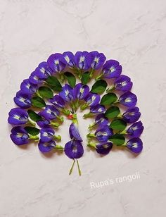 purple flowers with green leaves arranged in the shape of a triangle on a white surface