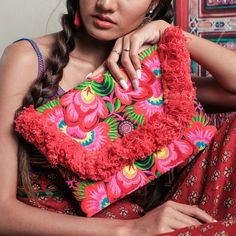 a woman sitting on a couch holding a red pillow