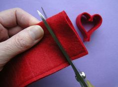 someone is cutting fabric with scissors and a heart shaped object in the corner behind them