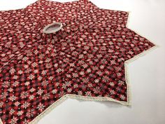 a red and white star shaped table cloth with lace trimming on the edge, sitting on a white surface