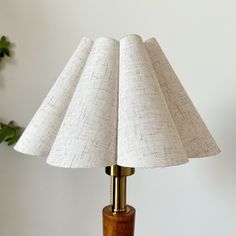 a wooden table with a lamp on top of it and a plant in the background