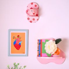 there is a pink wall with two pictures on it and a flower in a vase